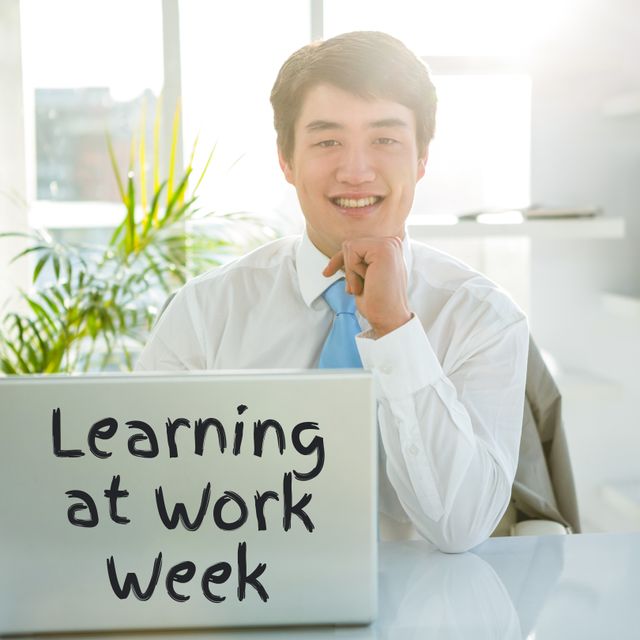 Confident young man in office celebrating Learning at Work Week. Ideal for corporate newsletters, learning initiatives, or HR campaigns highlighting growth and professional development at work.