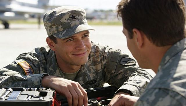 Smiling us army soldier leaning on equipment at airfield, talking with fellow serviceman