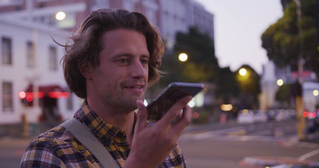 Young Man Using Smartphone Voice Assistant on Urban Street at Dusk - Download Free Stock Images Pikwizard.com