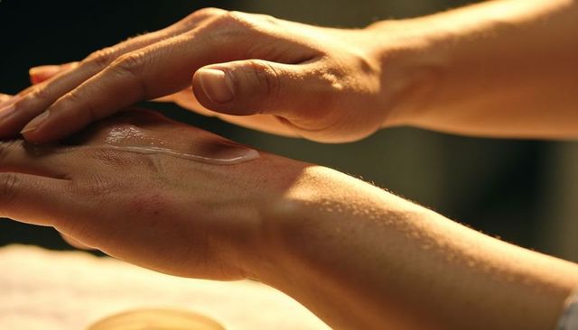 Applying moisturizer to hands with warm glow and detailed skin texture for skincare