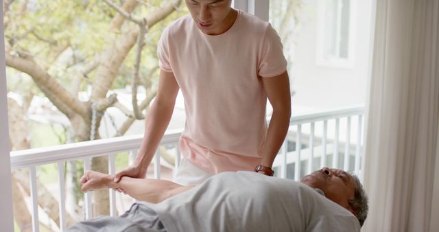 Young Caregiver Assisting Elderly Man with Stretching Exercise - Download Free Stock Images Pikwizard.com