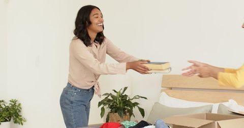Woman organizing wardrobe with visible joy in modern bedroom