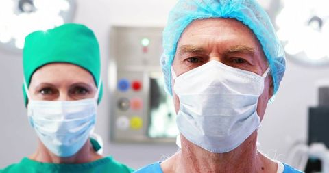 Senior surgeon leading surgical team in scrub cap and mask in operating room