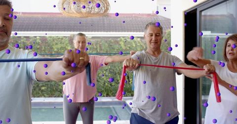 Mature adults performing resistance band workout on covered patio by pool, group training