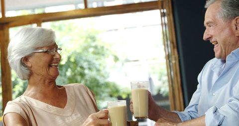 Happy Senior Couple Toasting with Beverages in Cheerful Atmosphere