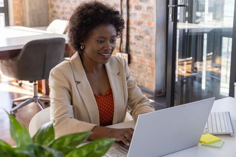 Professional Woman Typing on Laptop in Modern Office Environment