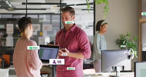 Smiling coworkers collaborating with laptop and smartphone in bright modern coworking office