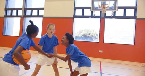 Diverse girls embracing teamwork on basketball court