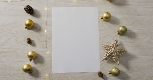 Image of christmas decorations with white card and copy space on wooden background. christmas, tradition and celebration concept.