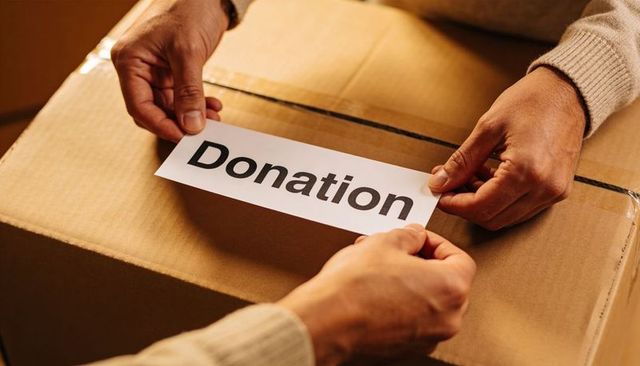 Hands labeling donation box for charity packing, community support and volunteer teamwork