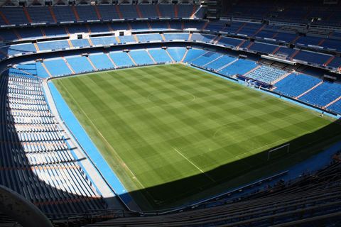 Empty Blue-Seated Football Stadium Featuring Striped Green Pitch from Bird's-Eye View