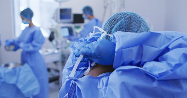 African american female surgeon wearing surgical cap, putting face mask on in operating theatre - Download Free Stock Photos Pikwizard.com