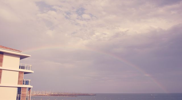 Rainbow Over Distant Ocean Near Coastal Building - Download Free Stock Photos Pikwizard.com