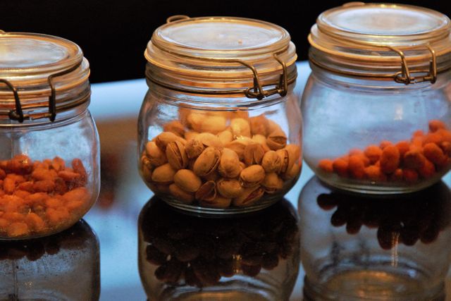 Glass Jars with Assorted Nuts and Snacks on Reflective Surface - Download Free Stock Photos Pikwizard.com
