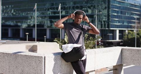 Young African American Man Adjusting Headphones on Urban Terrace Listening to Music
