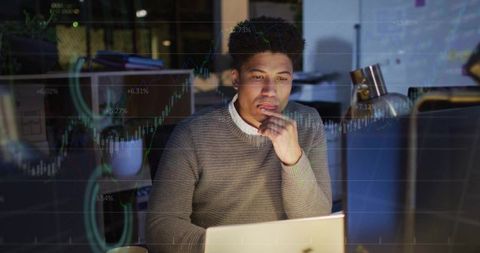 Focused African American Man Analyzing Financial Data on Laptop in Office Setting