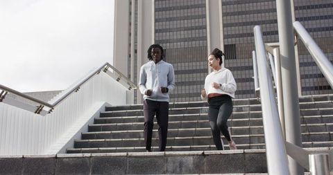 Diverse Friends Jogging Down Urban Steps Exercising Together in City Plaza