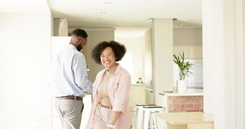Smiling diverse couple enjoying bright modern kitchen with brick breakfast bar and island