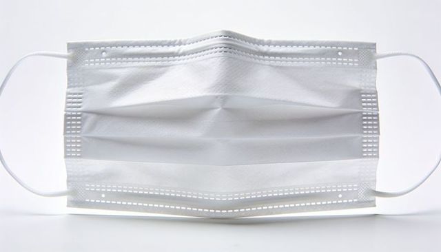 Disposable white surgical mask showing pleats, nose strip and ear loops for ppe healthcare protectio