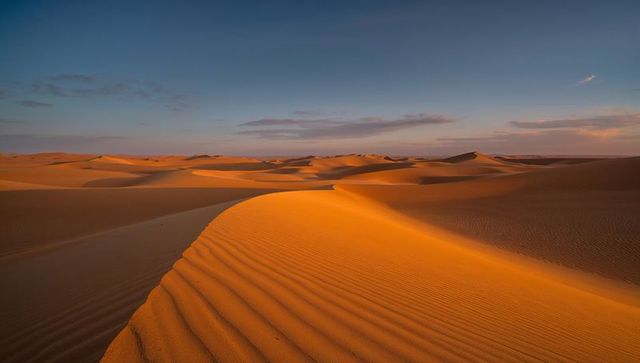 Glowing sand dune ridge stretching across golden desert at low sun revealing ripples