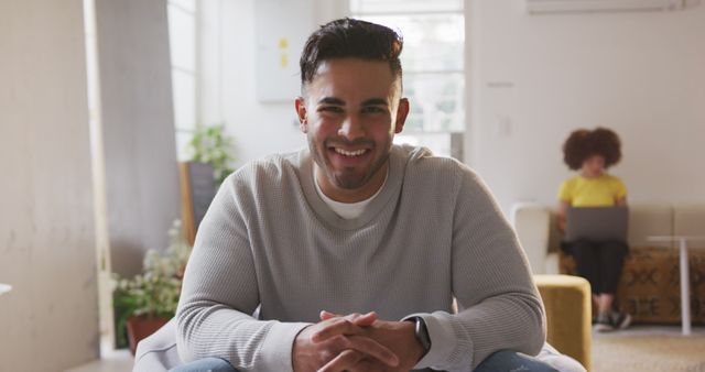 Young man enjoying a relaxed moment in a comfortable, modern home. Ideal for use in lifestyle blogs, interior design inspiration, advertisements showcasing comfortable living, social media posts emphasizing positivity and relaxation, or promotional materials for casual wear brands.