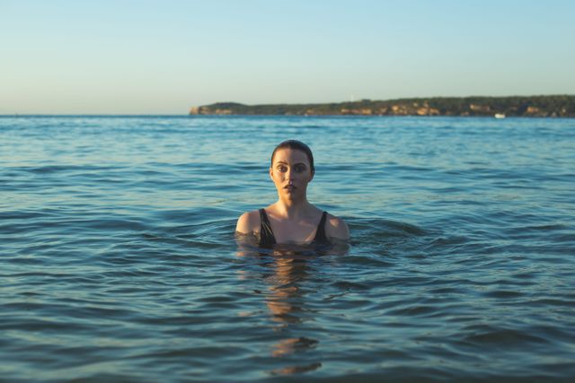 Image of a woman swimming in the ocean during sunset. The scene reflects a peaceful and calming atmosphere, making it ideal for wellness and relaxation content, travel and tourism promotions, or nature-inspired advertisements.