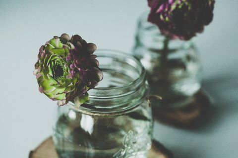 Rustic floral arrangement in glass jar on wooden coaster
