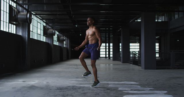 Shirtless african american man skipping the rope in an empty urban building. urban fitness and healthy lifetyle.