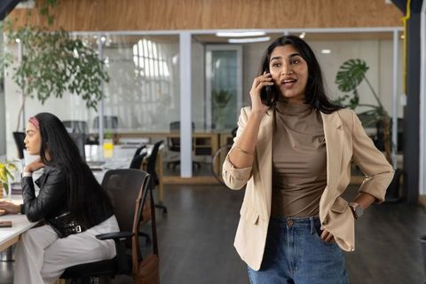 Confident young professional talking on phone in modern coworking space with team