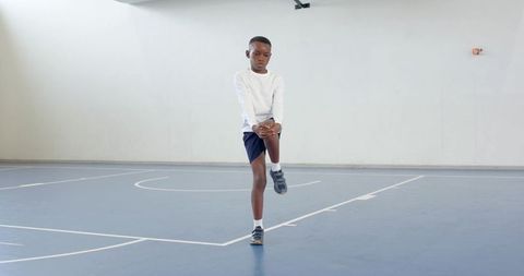 Young Athlete Stretching Knee on Indoor Basketball Court