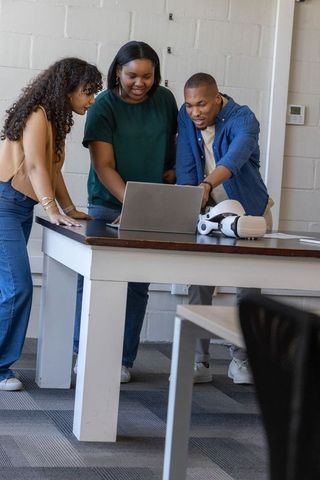 Multicultural team collaborating over laptop with vr headset in casual classroom workspace