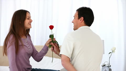 Man Gifting Rose to Smiling Girlfriend at Home