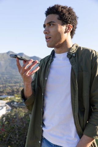 Man Recording Voice Note with Scenic Mountain View Background