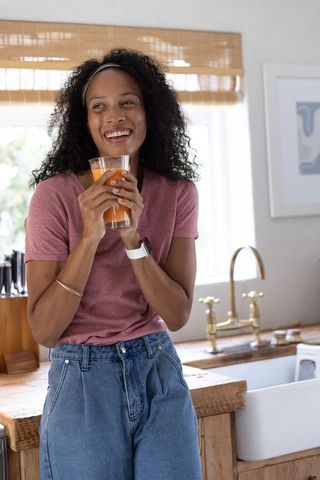 African american woman enjoying orange juice while leaning on rustic kitchen counter