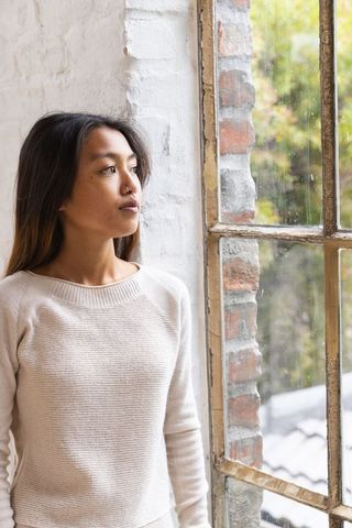 Asian Woman Gazing Through Vintage Loft Window