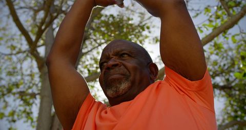 Senior Man Practicing Yoga Outdoors in Bright Orange Shirt