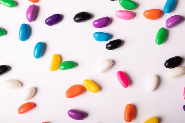 Bright and colorful candies scattered on a white background, creating a playful and fun atmosphere. Ideal for use in advertisements, social media posts, and marketing materials related to sweets, desserts, and confectionery. Perfect for adding a touch of color and joy to any project.