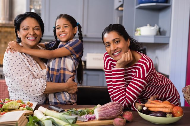 Three generations of women smiling and bonding in a kitchen while preparing vegetables. Ideal for use in advertisements promoting family values, healthy eating, and home cooking. Can be used in articles about family life, nutrition, and intergenerational relationships.