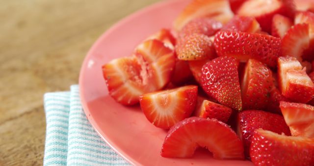 Freshly sliced strawberries are arranged on a pink plate, with copy space. Their vibrant red color and juicy texture make them an appetizing choice for a healthy snack or dessert ingredient.