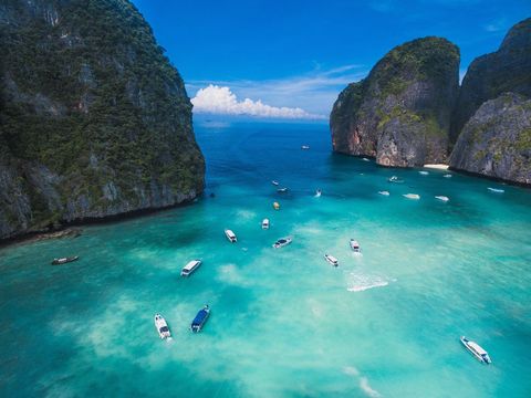 Soaring over turquoise lagoon with boats and dramatic limestone cliffs, tropical paradise