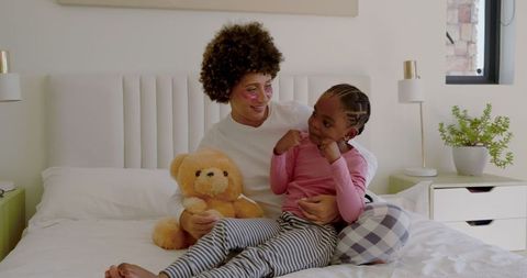 Playful African American Mother and Daughter Bonding with Teddy Bear
