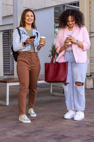 African american friends walking with coffee and smartphone, casual urban morning