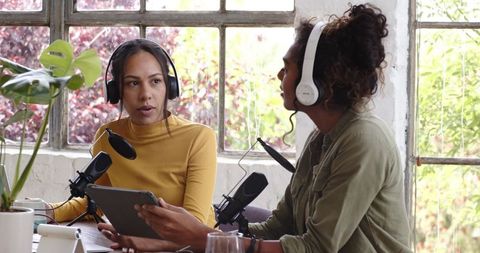 Two female podcasters recording creative discussion in modern studio