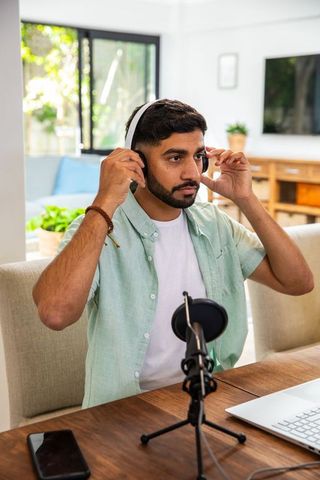 Man Adjusting Headphones While Podcasting at Home Office