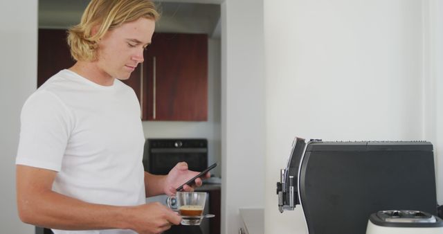 Man making coffee while using smartphone in kitchen - Download Free Stock Images Pikwizard.com