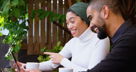 Happy Couple Enjoying Coffee and Viewing Smartphone in Cafe