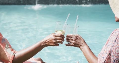 Senior Friends Relax Poolside Toasting with Drink Cups