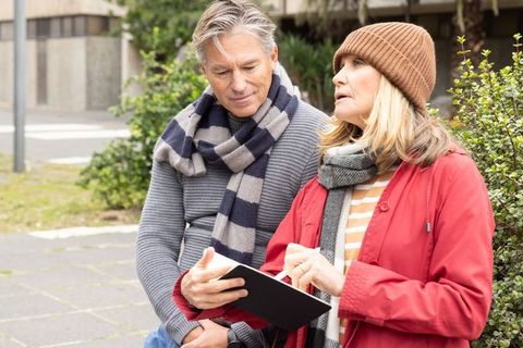 Senior couple using tablet outdoors for travel planning, learning technology, connection