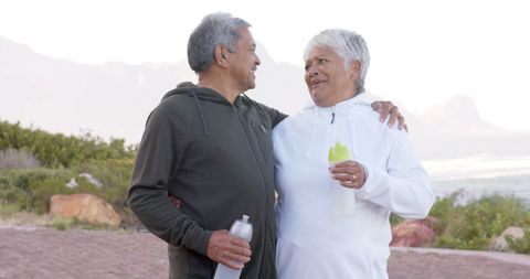 Senior Couple Embracing Outdoors with Water Bottles