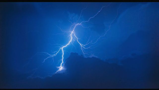 Dramatic lightning bolt illuminating thunderous night sky